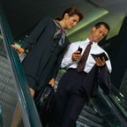 Business Man and Woman Riding Escalator