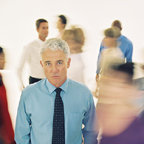 Man With Tie Standing To the Side In Blurred Crowd
