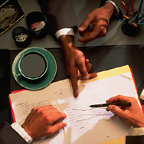 Three Hands Over A Desk